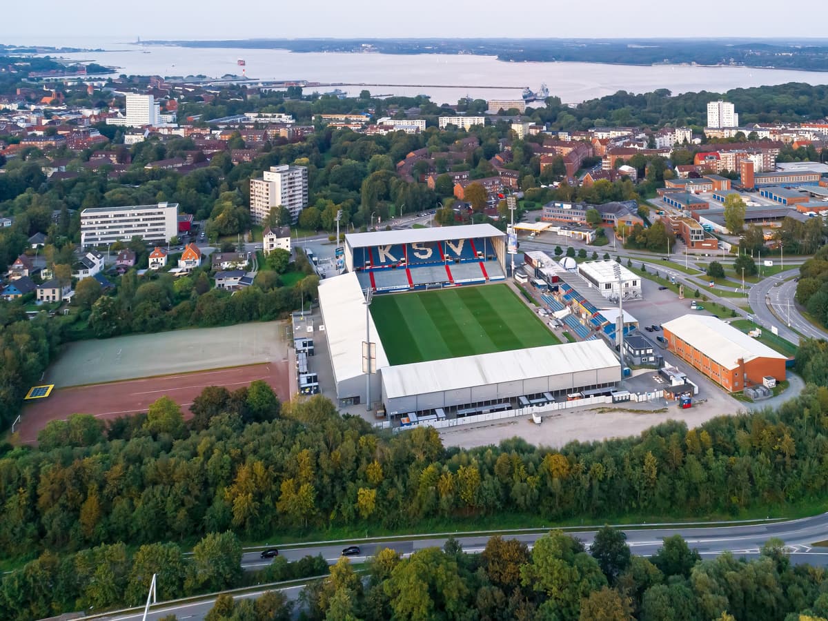 Luftbild des Holstein-Stadions in Kiel, dahinter Wohnviertel und die Kieler Förde