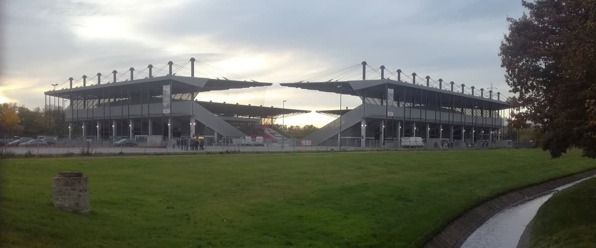 Das Stadion an der Hafenstraße in Essen von außen mit zwei Tribünenecken und Rasenfläche in der Abenddämmerung.