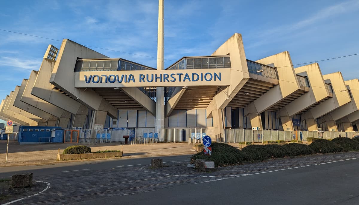 Außenansicht des Vonovia Ruhrstadions mit den markanten schrägen Betonstützen und dem Stadionschriftzug über dem Eingang.